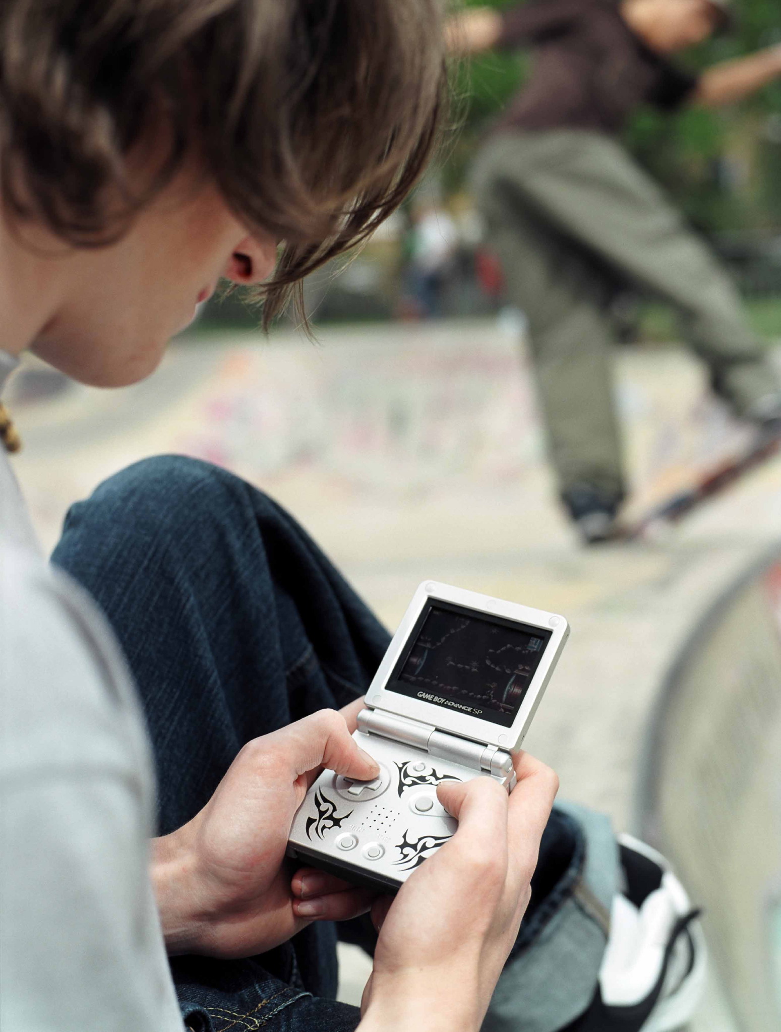 A man with a large nostril playing on a Game Boy Advance SP